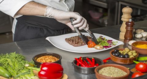 chef preparing beef steak for service with salad and grilled vegetable