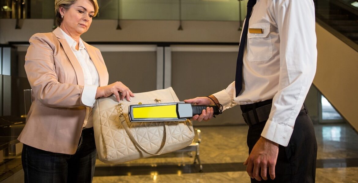 Airport security officer using a metal detector to check a bag