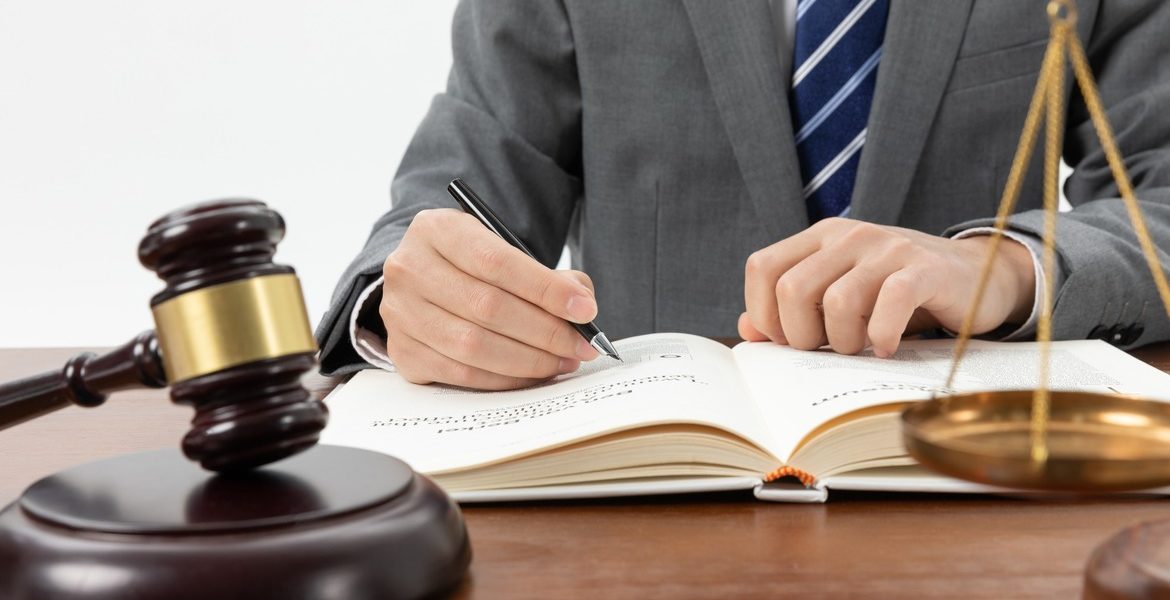 closeup-shot-of-person-writing-in-book-with-gavel-on-the-table (1)