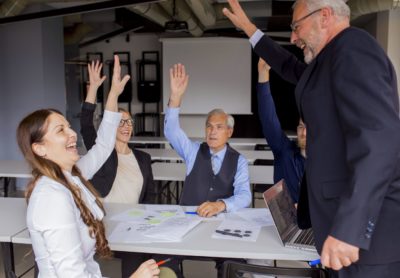 felices-empresarios-exitosos-levantando-sus-manos-reunion-consejo