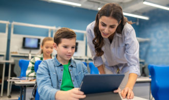 Woman looking into tablet of student boy